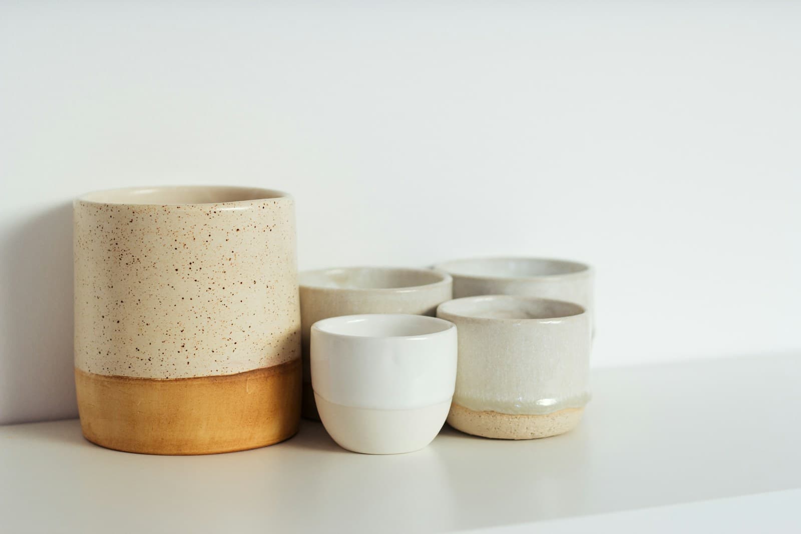 A collection of handmade cream and ochre ceramic vessels in soft natural light